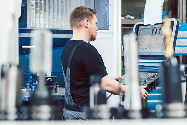 Worker in industrial workshop programming a cnc lathe